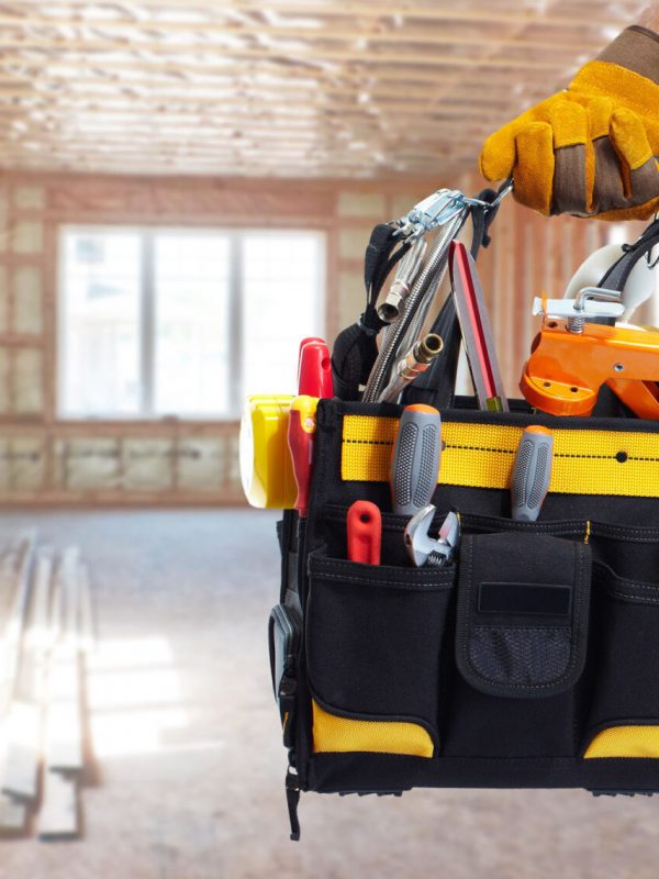 Builder handyman with construction tools. House renovation background.